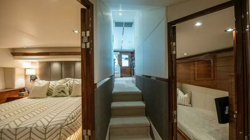 Slide: The Image of Lower Deck Corridor and Staterooms This image showcases the lower deck corridor of the 2023 Viking 64 Convertible, with access to luxurious staterooms. The master suite to the left features a spacious layout with a plush bed and elegant lighting. On the right, a cozy guest cabin provides a - 7600524