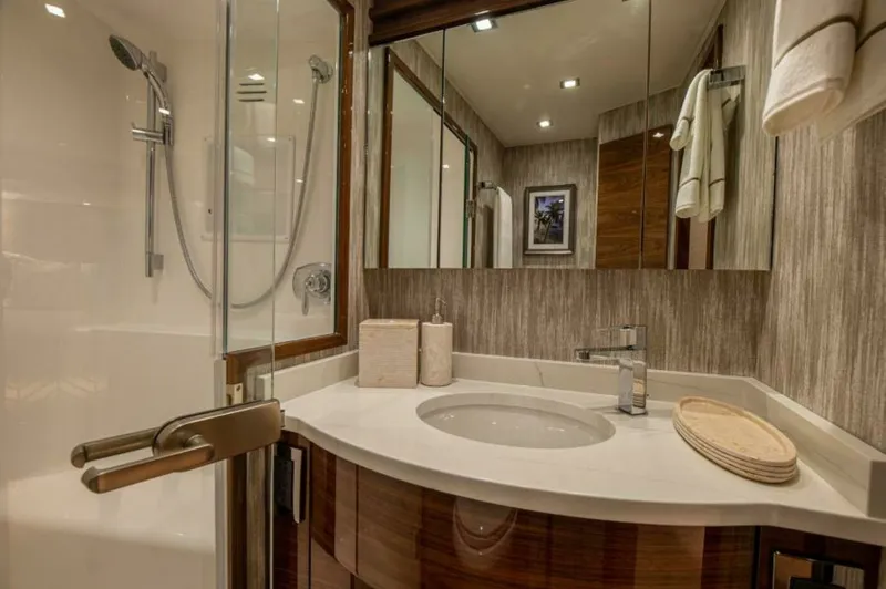 Slide: The Image of Elegant En-Suite Bathroom This luxurious en-suite bathroom on the Viking 64 Convertible features a modern glass-enclosed shower and sleek, polished fixtures. The elegant vanity is complemented by a rich wood finish and a pristine countertop, offering both style and functionality. - 7530846