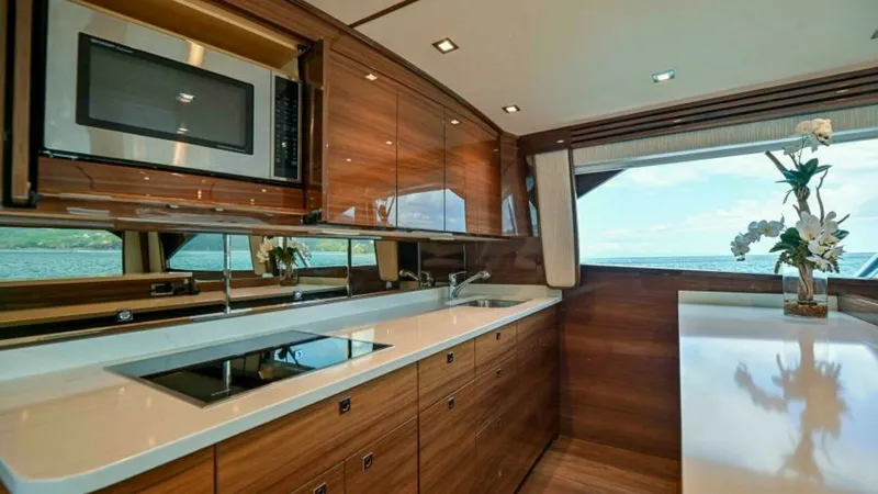 Slide: The Image of Modern Galley with Ocean View This sleek galley on the 2023 Viking 64 Convertible features high-gloss wood cabinetry and top-of-the-line appliances, including a built-in microwave and induction cooktop. Expansive countertops offer ample space for meal preparation, while large windows - 7600516
