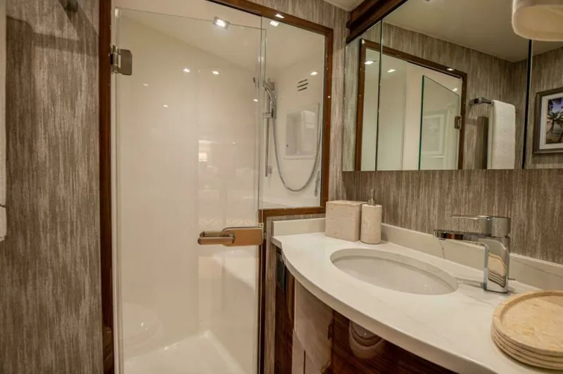 Slide: The Image of Elegant Ensuite Bathroom with Shower This stylish ensuite bathroom on the 2023 Viking 64 Convertible features a sleek glass-enclosed shower, offering a modern and luxurious touch. The curved vanity is topped with a polished countertop, complemented by contemporary fixtures and ample storage. - 7530847