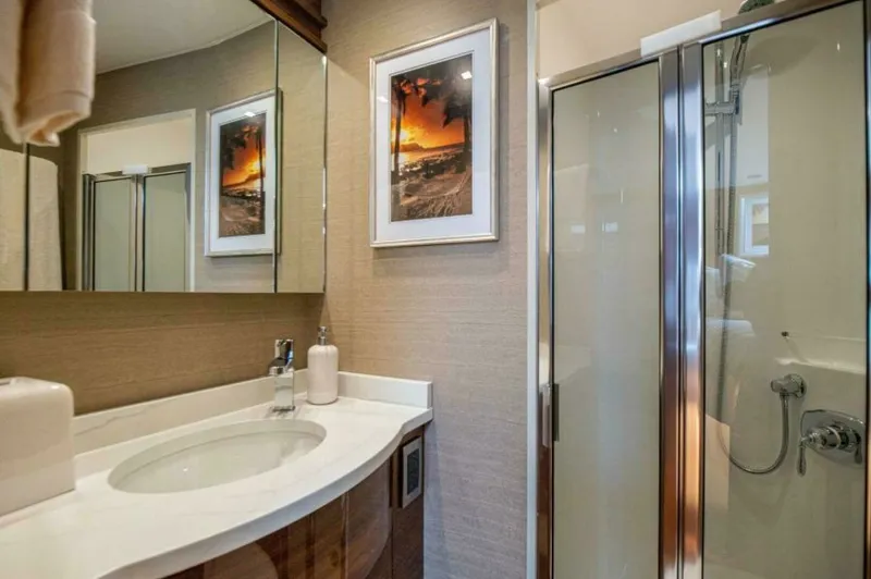 Slide: The Image of Elegant Ensuite Bathroom This beautifully appointed ensuite bathroom on the 2023 Viking 64 Convertible features a sleek glass-enclosed shower and a stylish vanity with a polished countertop. The warm wood finishes complement the modern fixtures, while the artful decor adds a touc - 7530858