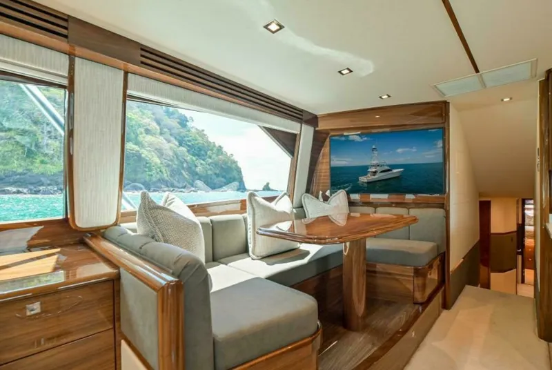 Slide: The Image of Elegant Interior Dining Nook The dining nook of the 2023 Viking 64 Convertible features luxurious upholstery and polished wood finishes, offering a comfortable space for meals or relaxation. Large windows provide breathtaking views of the surrounding seascape, enhancing the ambiance - 7530838