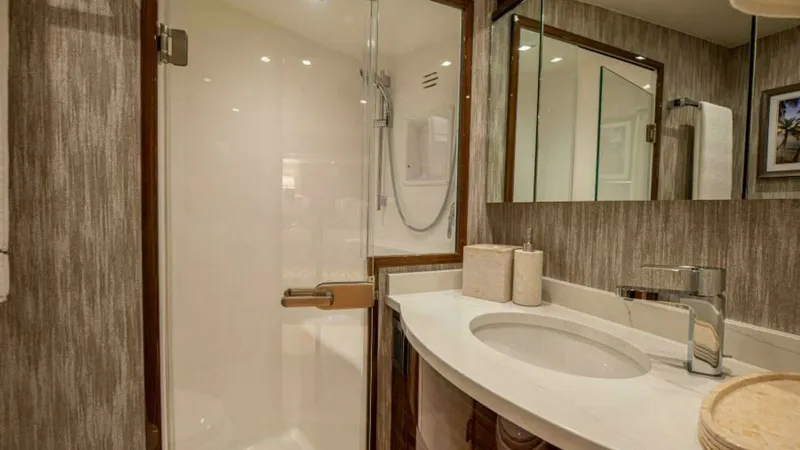 Slide: The Image of Elegant Ensuite Bathroom with Shower This stylish ensuite bathroom on the 2023 Viking 64 Convertible features a sleek glass-enclosed shower, offering a modern and luxurious touch. The curved vanity is topped with a polished countertop, complemented by contemporary fixtures and ample storage. - 7600529