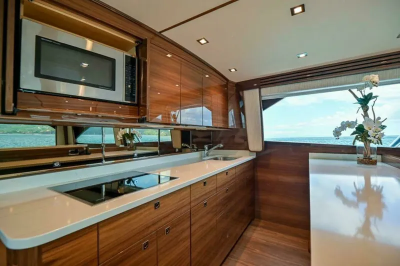 Slide: The Image of Modern Galley with Ocean View This sleek galley on the 2023 Viking 64 Convertible features high-gloss wood cabinetry and top-of-the-line appliances, including a built-in microwave and induction cooktop. Expansive countertops offer ample space for meal preparation, while large windows - 7530834