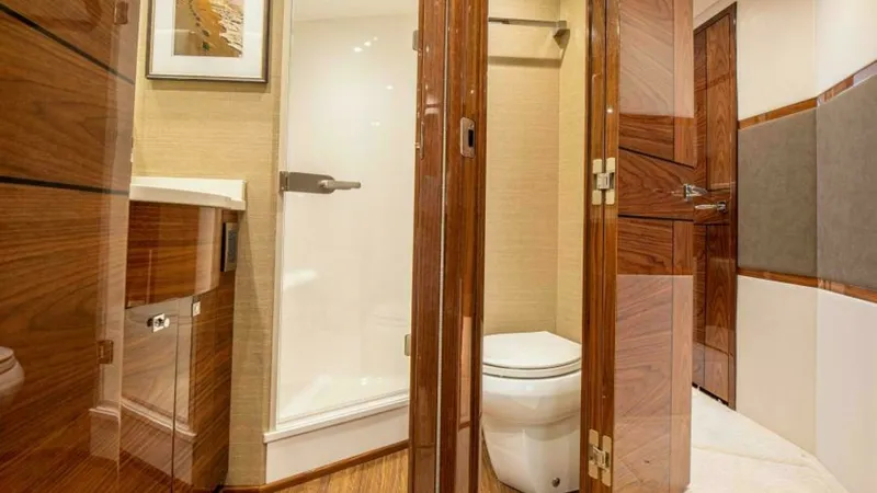 Slide: The Image of Luxurious Ensuite Bathroom View This image showcases the elegant ensuite bathroom of the 2023 Viking 64 Convertible. Rich wooden cabinetry and doors contrast beautifully with the modern fixtures, offering both style and functionality. The shower area features sleek glass doors, and the - 7600532