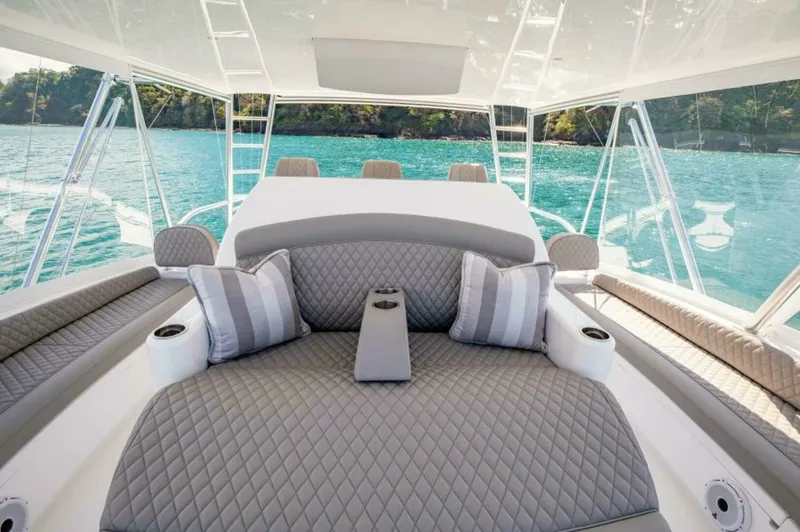 Slide: The Image of Flybridge Lounge Seating Area The flybridge of the 2023 Viking 64 Convertible features a luxurious lounge seating area with plush, quilted cushions and tasteful accent pillows. The spacious layout provides ample room for relaxation, while the panoramic views through the surrounding cl - 7530827