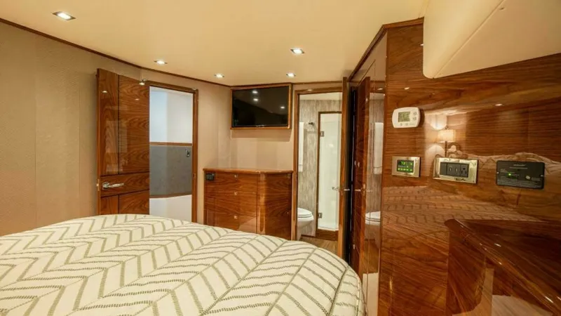 Slide: The Image of Luxurious Master Stateroom Interior The master stateroom of the 2023 Viking 64 Convertible offers an elegant retreat with high-gloss wood finishes and soft ambient lighting. The spacious layout features a plush, patterned bedspread, complemented by modern conveniences like a wall-mounted TV - 7600527