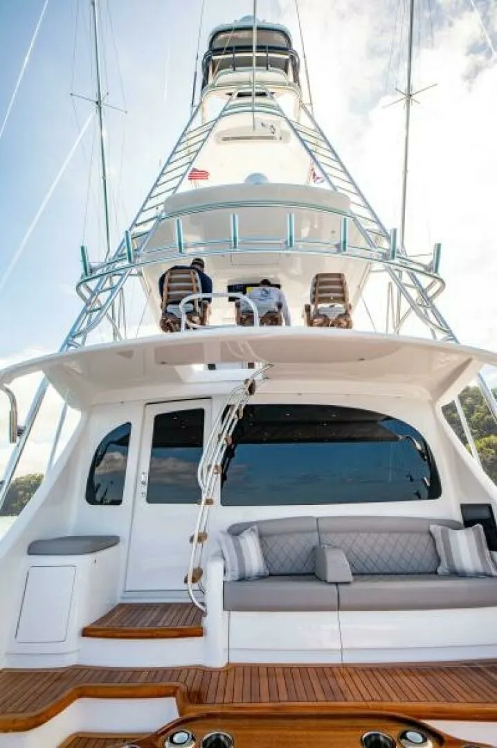 Slide: The Image of Aft Deck and Tower View The aft deck of the 2023 Viking 64 Convertible 'Twin Reels' showcases a spacious seating area with plush cushions, ideal for relaxation. Above, the tower offers a commanding view, perfect for navigation and sport fishing. The high-quality teak decking and - 7530860