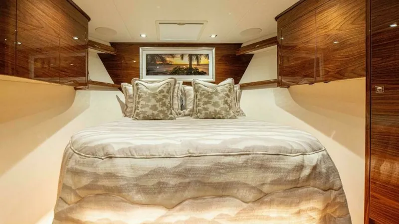 Slide: The Image of Luxurious Forward Stateroom This elegant forward stateroom on the 2023 Viking 64 Convertible features a plush centerline queen berth with exquisite bedding. The high-gloss wood cabinetry provides ample storage and adds a touch of sophistication, while recessed lighting creates a war - 7600537