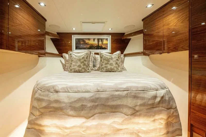 Slide: The Image of Luxurious Forward Stateroom This elegant forward stateroom on the 2023 Viking 64 Convertible features a plush centerline queen berth with exquisite bedding. The high-gloss wood cabinetry provides ample storage and adds a touch of sophistication, while recessed lighting creates a war - 7530855