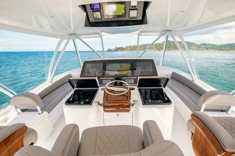 Slide: The Image of Flybridge Helm Station The helm station on the flybridge of the 2023 Viking 64 Convertible offers a commanding view of the surrounding waters. It features a state-of-the-art navigation system with multiple displays and ergonomic controls. The luxurious, quilted seating and teak - 7530861