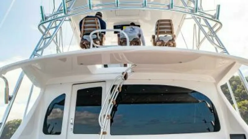 Slide: The Image of Aft Deck and Tower View The aft deck of the 2023 Viking 64 Convertible 'Twin Reels' showcases a spacious seating area with plush cushions, ideal for relaxation. Above, the tower offers a commanding view, perfect for navigation and sport fishing. The high-quality teak decking and - 7600542