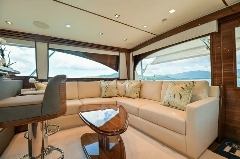 Slide: The Image of Luxurious Salon with Panoramic Views This elegant salon aboard the 2023 Viking 64 Convertible showcases a spacious seating area with plush, cream-colored upholstery. Large windows provide breathtaking panoramic views, creating a bright and inviting atmosphere. The polished wooden table and c - 7530829