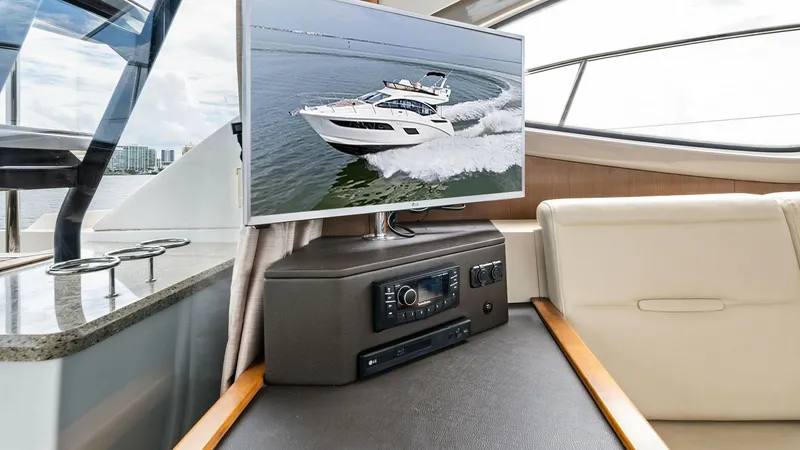 Slide: The Image of Salon Entertainment Area with TV The entertainment area of the Sea Ray 400 Fly features a mounted flat-screen TV and a sleek audio system, offering a modern touch for onboard leisure. The seating area is upholstered in plush, light-colored materials, providing comfort and elegance. Large - 7762697