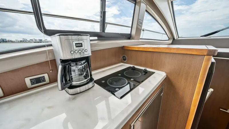 Slide: The Image of Flybridge Galley with Cooktop and Views This inviting flybridge galley on the 2018 Sea Ray 400 Fly features a sleek, modern design. The marble countertop houses a compact cooktop and a stylish coffee maker, perfect for onboard culinary adventures. Large windows offer panoramic views, creating a - 7762694