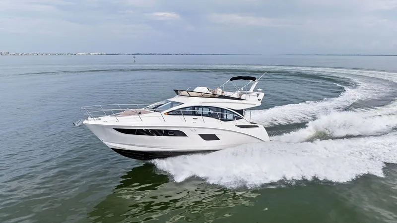 Slide: The Image of Dynamic Bow View at Sea The Sea Ray 400 Fly, Tee Time III, elegantly slices through the water, showcasing its sleek and modern design. The vessel's aerodynamic lines and expansive windows offer a glimpse into its luxurious interior, while the spacious flybridge provides an eleva - 7762738