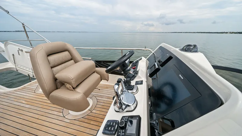 Slide: The Image of Flybridge Helm Station with Seating The flybridge helm station of the Sea Ray 400 Fly features a sleek, modern dashboard equipped with advanced navigation displays and controls. The helm chair offers plush, ergonomic seating, providing comfort during long voyages. Surrounded by a teak deck, - 7762713