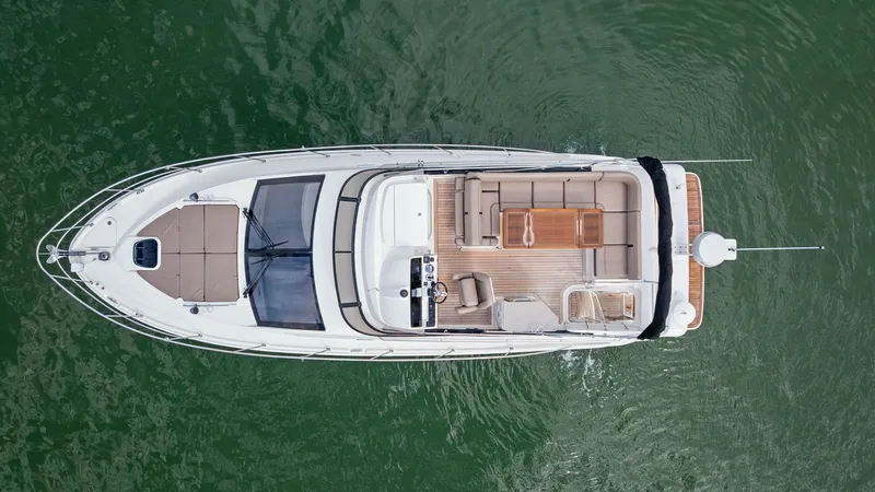 Slide: The Image of Aerial View of Flybridge and Deck This overhead shot captures the spacious flybridge and deck of the 2018 Sea Ray 400 Fly, Tee Time III. The flybridge is equipped with ample seating and a sleek helm station, perfect for navigating with a panoramic view. The teak decking adds a touch of el - 7762724
