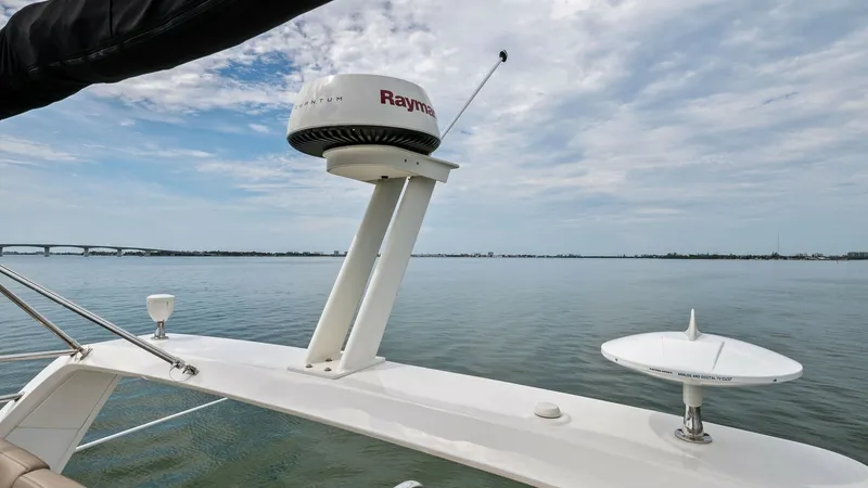 Slide: The Image of Flybridge Electronics and Radar Array This image showcases the advanced electronics and radar array on the flybridge of the 2018 Sea Ray 400 Fly, Tee Time III. The Raymarine radar system is prominently featured, ensuring precise navigation and safety. The expansive water views highlight the v - 7762718