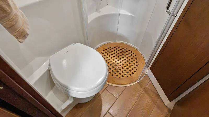 Slide: The Image of Compact Enclosed Yacht Bathroom This well-designed bathroom on the 2018 Sea Ray 400 Fly features a sleek, modern toilet and a rounded shower with a stylish wooden grate floor. The use of high-quality materials and efficient layout maximizes space and comfort, providing a luxurious exper - 7762704