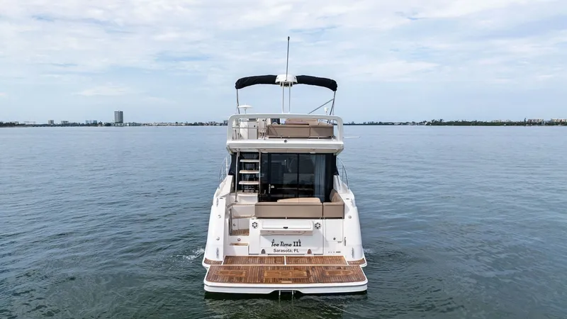 Slide: The Image of Aft View with Teak Swim Platform The 2018 Sea Ray 400 Fly, Tee Time III, showcases a spacious aft design with a luxurious teak swim platform. The flybridge is accessible via a sleek staircase, offering panoramic views. The aft deck features comfortable seating, perfect for social gatheri - 7762722
