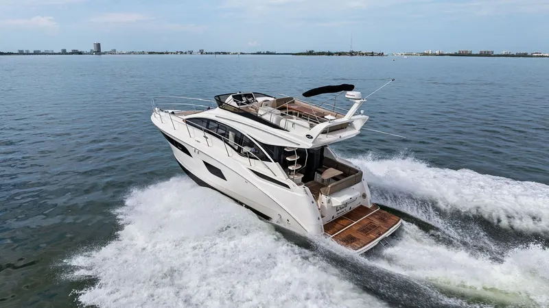 Slide: The Image of Aerial View of Flybridge and Aft Deck This dynamic aerial shot captures the sleek design of the Sea Ray 400 Fly's flybridge and aft deck. The vessel, cutting through the water, showcases its spacious flybridge equipped with comfortable seating and a helm. The teak-finished aft deck offers eas - 7762743