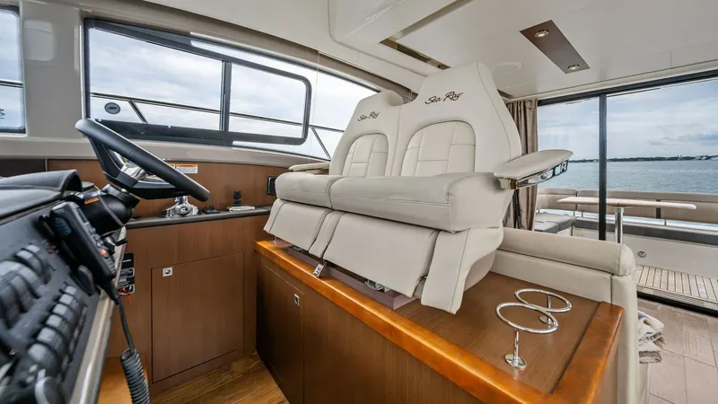 Slide: The Image of Helm Station with Twin Seating This image showcases the helm station of the Sea Ray 400 Fly, featuring luxurious twin seating with elegant upholstery and armrests. The well-equipped control area includes state-of-the-art navigation systems, providing a commanding view through large win - 7762687