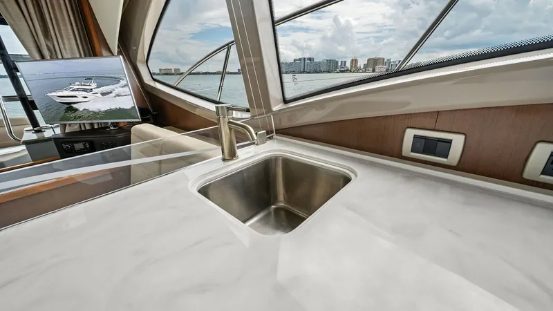 Slide: The Image of Modern Galley with Scenic Views The galley aboard the 2018 Sea Ray 400 Fly features a sleek, modern countertop with an integrated stainless steel sink. Large windows provide abundant natural light and panoramic views, enhancing the open and airy atmosphere. The space is designed for bot - 7762695