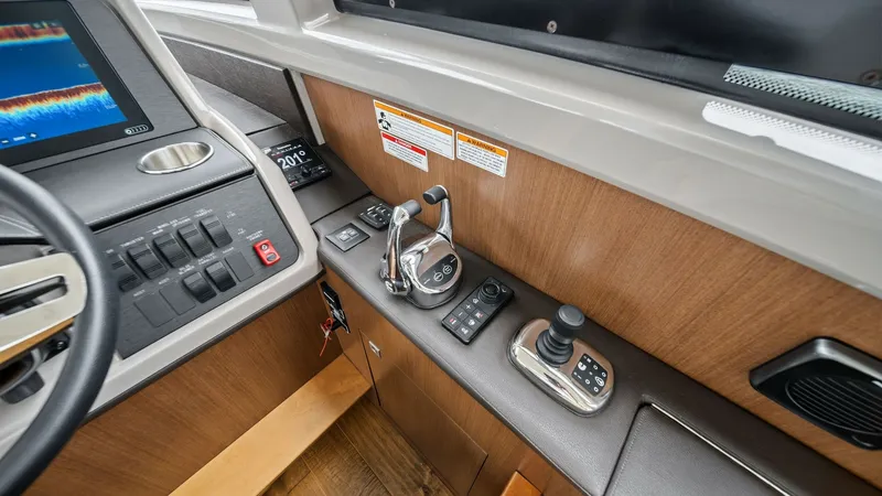 Slide: The Image of Helm Station with Controls The helm station of the 2018 Sea Ray 400 Fly features an ergonomic layout with state-of-the-art controls and instrumentation. The polished wood paneling complements the sleek design of the throttle and joystick, offering precision handling. Enhanced by a - 7762689