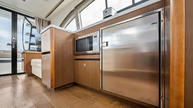 Slide: The Image of Galley with Stainless Steel Appliances The galley of the 2018 Sea Ray 400 Fly 'Tee Time III' features sleek stainless steel appliances, including a built-in microwave and refrigerator. The warm wood cabinetry complements the modern design, while large windows provide ample natural light. This - 7762693