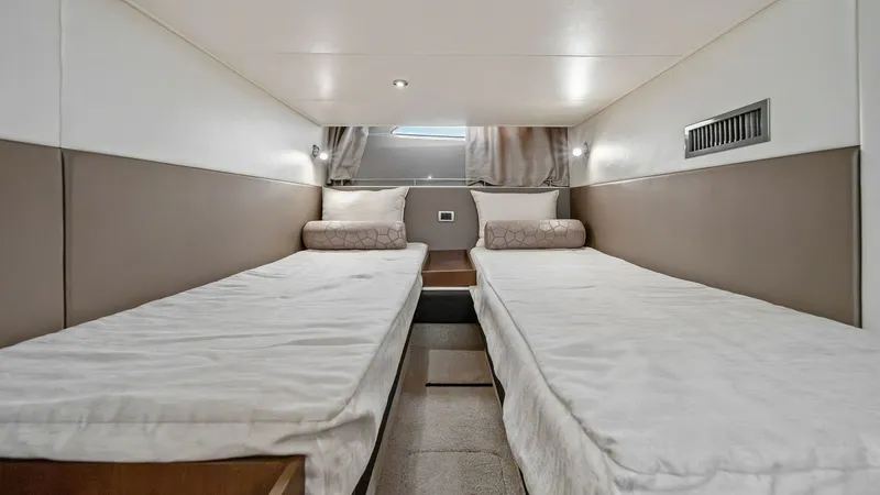 Slide: The Image of Twin Guest Stateroom This inviting twin guest stateroom on the 2018 Sea Ray 400 Fly offers comfortable accommodations with two parallel single beds. The room is designed with soft ambient lighting and plush bedding, providing a cozy retreat for guests. A sleek, modern aesthet - 7762705