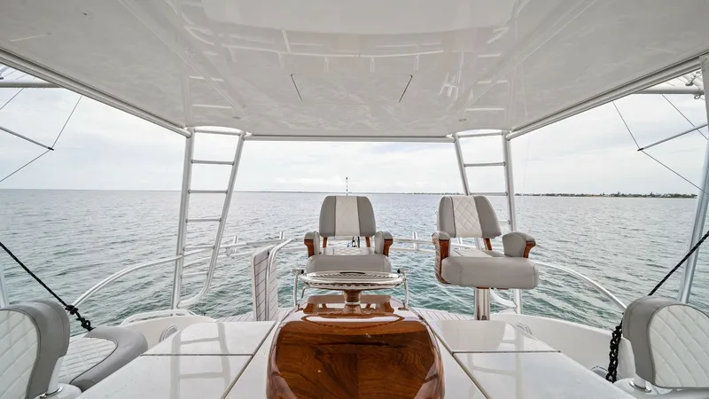 Slide: The Image of Flybridge Helm with Seating Area This image showcases the luxurious flybridge helm of the 2015 Viking 55 Convertible, featuring comfortable seating with high-quality upholstery. The helm offers an expansive view of the open water, perfect for both leisurely cruising and serious fishing. - 7584897