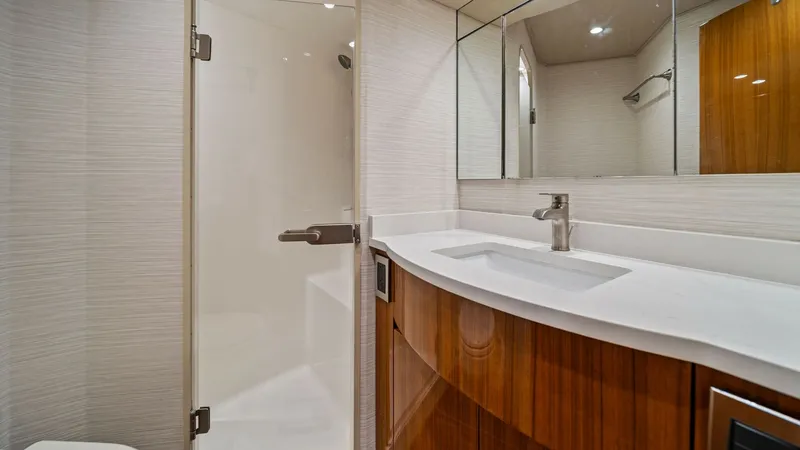 Slide: The Image of Elegant Ensuite Bathroom with Shower This stylish ensuite bathroom features a sleek glass-enclosed shower and a modern vanity with a polished faucet. The warm wood cabinetry complements the soft lighting, creating a luxurious and inviting atmosphere. The mirrored wall enhances the space, mak - 7584889