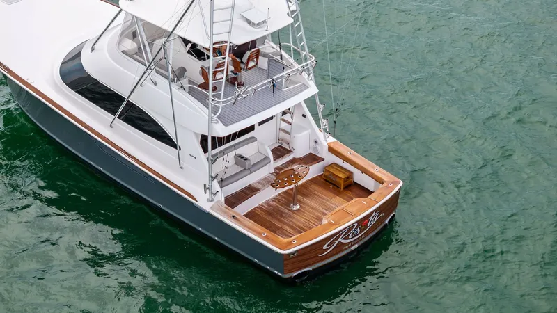 Slide: The Image of Aft Deck and Flybridge View This image showcases the spacious aft deck of the 2015 Viking 55 Convertible, featuring a beautifully finished teak deck with ample seating for relaxation and entertainment. The flybridge above provides a commanding view, equipped with advanced navigation - 7584923