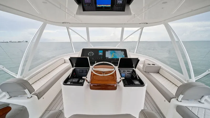 Slide: The Image of Flybridge Helm Station The flybridge helm station on the 2015 Viking 55 Convertible offers an impressive panoramic view. Equipped with modern navigation and control systems, the helm features a polished wooden steering wheel and advanced display screens. The surrounding cushion - 7584910