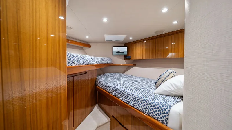 Slide: The Image of Guest Stateroom with Twin Berths This inviting guest stateroom features twin berths adorned with stylish bedding, offering comfort and elegance. The rich wood cabinetry provides ample storage and adds a touch of luxury to the space. Recessed lighting and a sleek flatscreen TV enhance the - 7584886