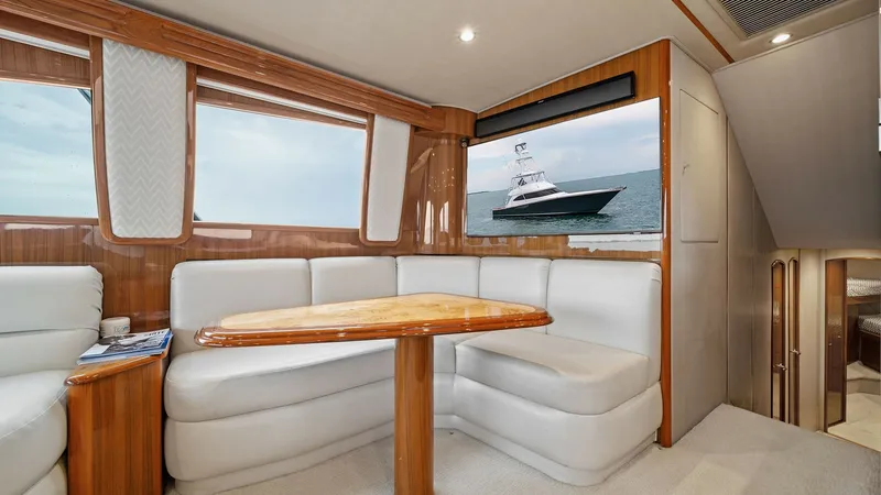 Slide: The Image of Main Salon with Dinette Area The main salon of the 2015 Viking 55 Convertible 'Rosita' features a stylish dinette area with plush white seating and a beautifully crafted wooden table. Large panoramic windows provide ample natural light and stunning ocean views. The space is equipped - 7584876