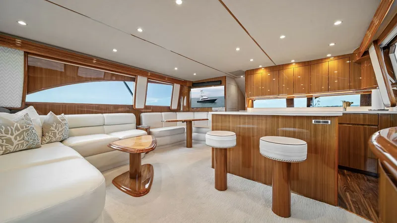 Slide: The Image of Spacious Salon with Galley View The salon of the 2015 Viking 55 Convertible 'Rosita' features an elegant open-plan layout, showcasing luxurious leather seating and a tastefully crafted wooden interior. Ample natural light pours in through large panoramic windows, enhancing the space's a - 7584874
