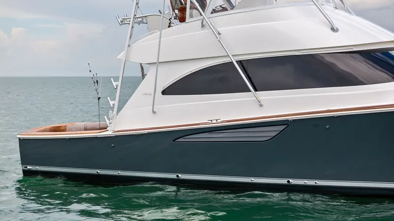 Slide: The Image of Starboard Profile with Flybridge This side view showcases the sleek design of the 2015 Viking 55 Convertible, highlighting its elegant lines and spacious flybridge. The polished hull glides smoothly through the water, while the ample windows provide natural light and stunning views. The - 7584928