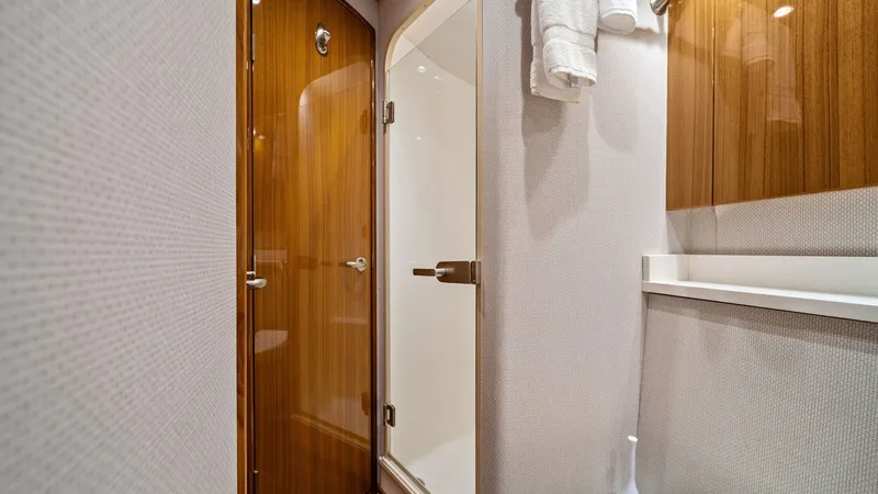Slide: The Image of Guest Bathroom with Shower This elegantly designed guest bathroom features a sleek enclosed shower with a glass door, offering both functionality and style. The warm wooden cabinetry complements the crisp, clean lines of the space, while modern fixtures add a touch of sophisticatio - 7584885