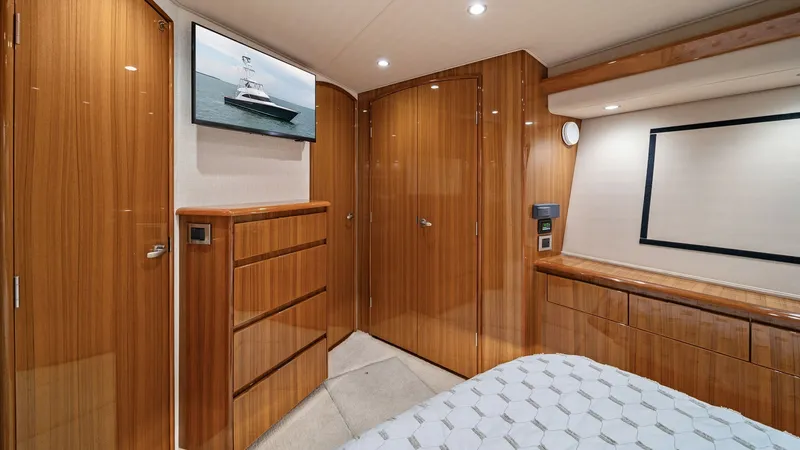 Slide: The Image of Master Stateroom with Elegant Woodwork The master stateroom of the 2015 Viking 55 Convertible exudes sophistication with its high-gloss wooden cabinetry and ample storage space. Soft lighting complements the luxurious bedding, creating an inviting atmosphere. The room is thoughtfully designed - 7584882