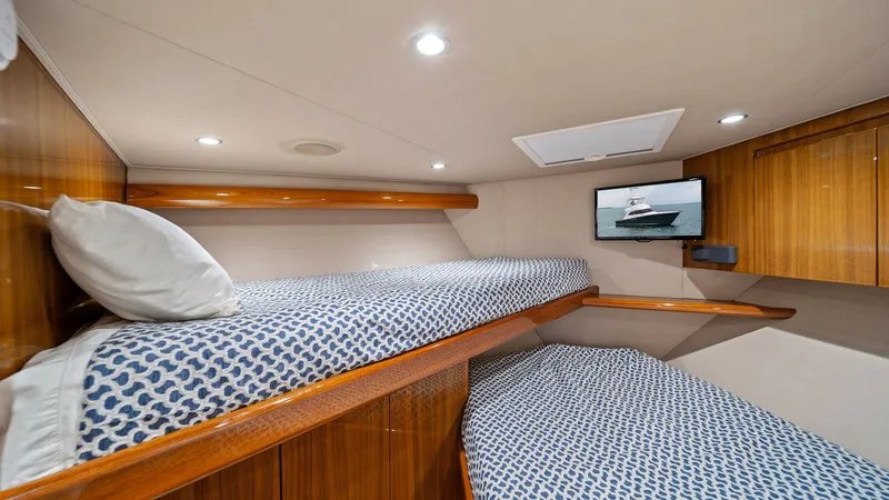Slide: The Image of Guest Cabin with Bunk Beds This inviting guest cabin on the 2015 Viking 55 Convertible 'Rosita' features twin bunk beds with elegant patterned bedding. The warm wood paneling adds a touch of luxury, while recessed lighting provides a cozy ambiance. A mounted flat-screen TV offers e - 7584888