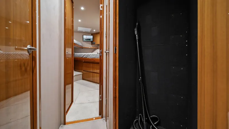 Slide: The Image of Corridor Leading to Stateroom This image showcases a well-lit corridor leading to the stateroom on the Viking 55 Convertible. The warm wood finishes of the cabinetry complement the plush carpet, creating a welcoming atmosphere. A closet space is visible on the right, offering convenie - 7584893
