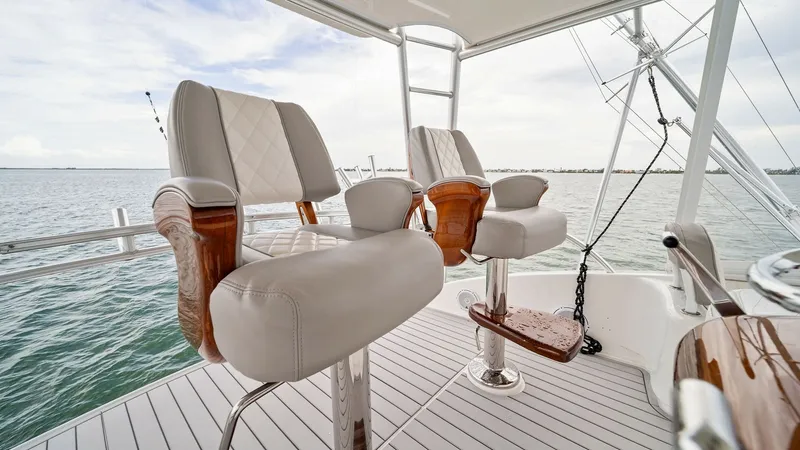 Slide: The Image of Flybridge Helm Seating Area This image showcases the flybridge helm seating area of the 2015 Viking 55 Convertible. Featuring two luxurious helm chairs with plush, cushioned seating and elegant wood accents, this area offers a commanding view of the surrounding waters. The spacious - 7584900