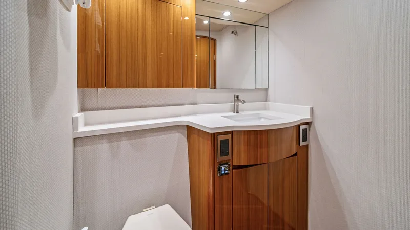 Slide: The Image of Elegant Vessel Bathroom Vanity This sophisticated bathroom on the 2015 Viking 55 Convertible 'Rosita' features a sleek, modern vanity with polished wood cabinetry and a seamless white countertop. The integrated sink and mirrored cabinet enhance functionality and style, while recessed l - 7584884