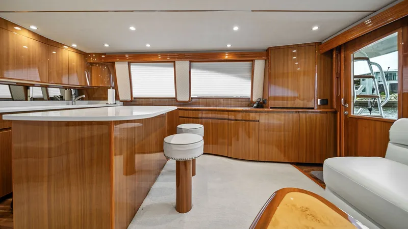 Slide: The Image of Spacious Salon with Barstools The salon of the 2015 Viking 55 Convertible offers a luxurious space with high-gloss wood finishes and plush seating. The open layout includes a stylish counter and ample natural light from large windows, creating an inviting atmosphere for relaxation or - 7584865