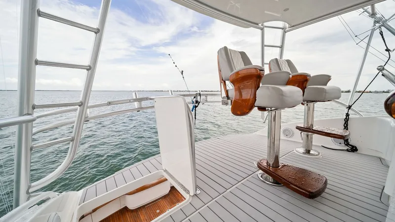 Slide: The Image of Flybridge with Helm Seating This image showcases the flybridge of the 2015 Viking 55 Convertible, featuring luxurious helm seating with polished wood and cushioned surfaces. The open layout offers panoramic ocean views, complemented by a robust fishing setup. Stainless steel accents - 7584898