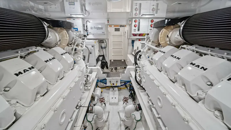 Slide: The Image of Engine Room with Twin MAN Engines This image showcases the immaculate engine room of the 2015 Viking 55 Convertible, featuring powerful twin MAN engines. The space is meticulously organized, highlighting advanced engineering with easy access to all essential systems. Bright lighting and c - 7584917