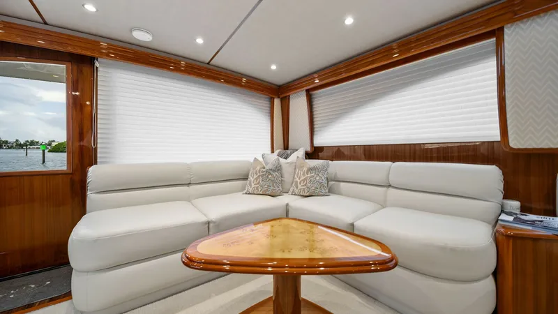 Slide: The Image of Luxurious Salon Seating Area This inviting salon on the 2015 Viking 55 Convertible features plush, cream-colored leather seating arranged in an L-shape, providing ample space for relaxation and socializing. The warm wood finishes and soft overhead lighting create an elegant and cozy - 7584862