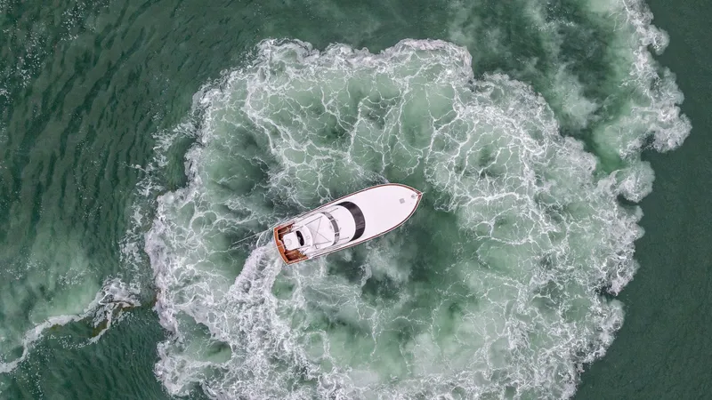 Slide: The Image of Aerial View of Rosita in Motion This dynamic aerial shot captures the Viking 55 Convertible, Rosita, creating a striking pattern in the water as it maneuvers. The powerful wake showcases the vessel's impressive performance and agility. With its sleek design and robust build, this 2015 m - 7584935